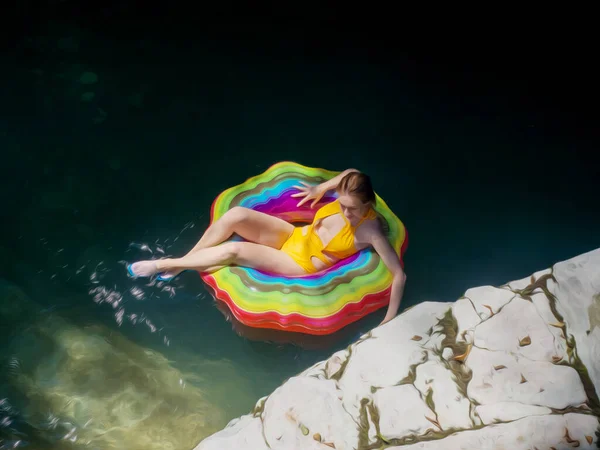 Una ragazza in un cerchio gonfiabile multicolore cavalca sull'acqua in un chiaro stagno turchese. Foto d'arte. Pittura ad olio imitazione. Illustrazione — Foto Stock