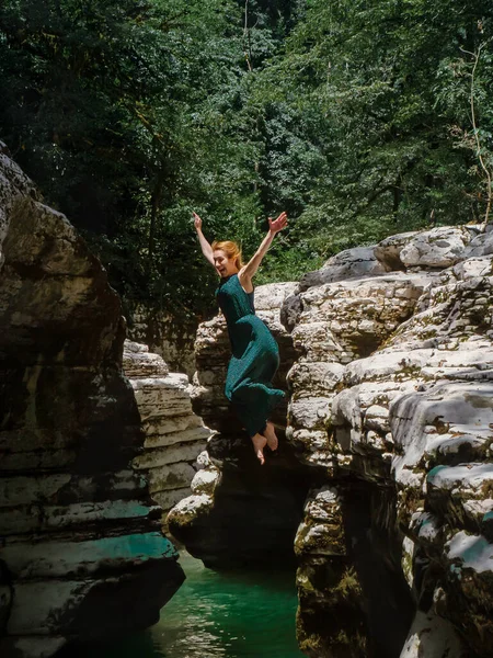 Una ragazza in abito vola dal canyon nel fiume turchese. Foto con filtro — Foto Stock