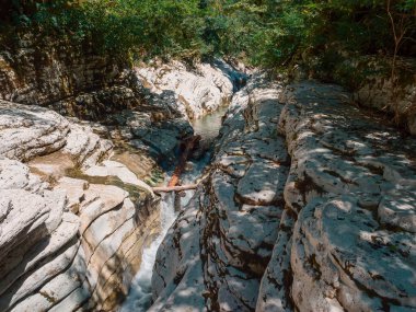 Dar bir vadide aralarında akan yosun ve ormanla kaplı büyük kanyonlar.