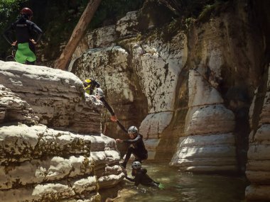 Rusya, Soçi 17.07.2021. Dalgıç kıyafetli insanlar güneşli bir günde nehirden pürüzsüz kanyonlardan sürünerek çıkarlar.