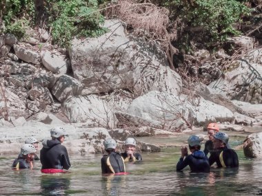 Rusya, Soçi 17.07.2021. Kasklı ve dalgıç kıyafetli bir grup insan yaz günü bir dağ nehrinde rafting yapıyor.