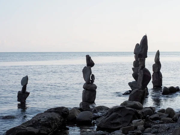 Удлиненные каменные пирамиды, построенные на берегу спокойного моря — стоковое фото