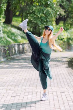 Zümrüt hip-hop elbiseli bir kız parkta sallanıyor.