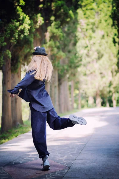 Mulher de roupas azuis e um chapéu em uma pose de dança em um beco no parque. Dançarino — Fotografia de Stock