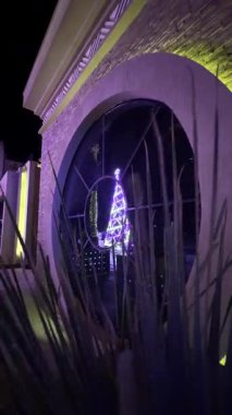 Aydınlatılmış Noel ağacı dairesel pencereye yansıdı.
