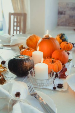 Şükran Günü aile yemeği için şenlik masası. Dekoratif balkabakları, fındıklar, koniler, dökülen yapraklar ve mumlarla iç kısımda sonbahar kompozisyonu. Doğal sonbahar dekoru. Seçici odak
