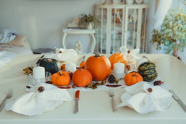 Şükran Günü aile yemeği için şenlik masası. Dekoratif balkabakları, fındıklar, koniler, dökülen yapraklar ve mumlarla iç kısımda sonbahar kompozisyonu. Doğal sonbahar dekoru. Seçici odak — Stok fotoğraf