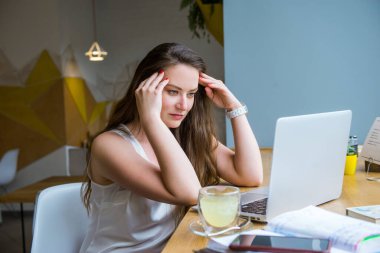Düşünceli, konsantre bir iş kadını kafeteryada çalışırken dizüstü bilgisayarına bakıyor. Uzaktan çalışma konsepti. Freelancer çalışma alanı. Boşluğu kopyala.