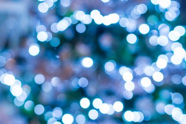 Koyu yeşil arka planda soyut mavi ve beyaz Bokeh festoon. Noel ağacındaki soğuk ışık çelenginden Bokeh. Noel, Yeni Yıl Festivali geçmişi.