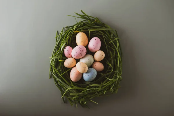 Top view χρωματιστά πασχαλινά αυγά σε πράσινο χόρτο φωλιά στο υποτονικό πράσινο φόντο. Εκλεπτυσμένη τόνωση. Καλό Πάσχα, ανοιξιάτικη ιδέα. Επίπεδη Lay, επιλεκτική εστίαση, αντίγραφο χώρου. — Φωτογραφία Αρχείου