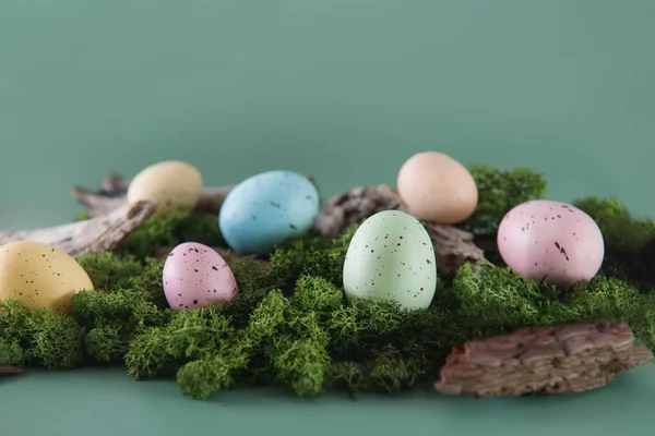Huevos de Pascua coloridos en un musgo y bosques sobre fondo verde apagado. Feliz cacería de Pascua. Enfoque selectivo. Copiar espacio. — Foto de Stock