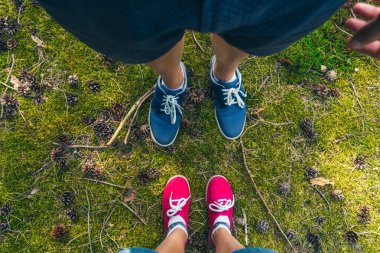 Koni ve ağaç dallarıyla yeşil çimlerin üzerinde duran renkli spor ayakkabılı adam ve kadına bakıyordum. Yaz ormanında yürüyen bir çift. Yerel seyahat ve doğada rahatlama. Dijital detoks.