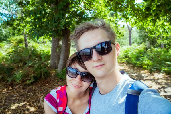 Romantic couple in sunglasses making selfie while walking in the summer forest. Local Traveling and relax in nature. Digital detox. Offline life. Capture the moment. Enjoy life. Copy space. — Stock Photo, Image