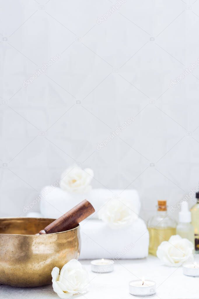 Spa and wellness massage setting with Tibetan singing bowl. Asian relaxing spa procedure with essential oils and sound healing therapy. Alternative medicine and body care. Vertical card. copy space.