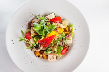 Vejetaryen salata ızgara sebze, beyaz peynir, taze domates, marul ve roka ceviz ve beyaz arka plan üzerinde izole beyaz plaka üzerinde kurutulmuş kekik ile dekore edilmiş kapatmak