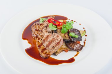 Restoran, haşlanmış sebze ve sos ile eti biftek sunmaktadır: kabak, patlıcan, havuç, mantar, bitki ve baharat beyaz tabakta izole ile dekore edilmiş