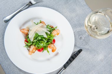 Top view Delicious salad with shrimps, arugula, cherry tomatoes and Parmesan cheese, seasoned with balsamic sauce on served for dinner restaurant table