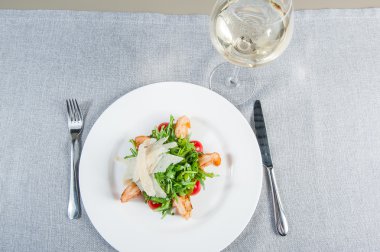 Top view Delicious salad with shrimps, arugula, cherry tomatoes and Parmesan cheese, seasoned with balsamic sauce on served for dinner restaurant table