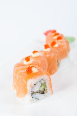 Traditional fresh japanese Salmon sushi rolls with shrimps, avocado and cucumber inside decorated with Red caviar on white plate isolated on a white background