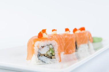 Traditional fresh japanese Salmon sushi rolls with shrimps, avocado and cucumber inside decorated with Red caviar on white plate isolated on a white background