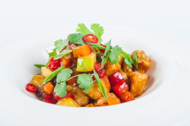 Tatlı - sebze ile Kızartma domuz geleneksel Japon yemeği yakın ekşi sos izole beyaz bir arka plan üzerinde yuvarlak bir tabak içinde maydanoz ile süslenmiş