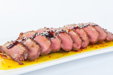 Otlar ve susam beyaz tabakta izole kavrulmuş Duck meme mango ve balsamik sosları ile süslenmiş