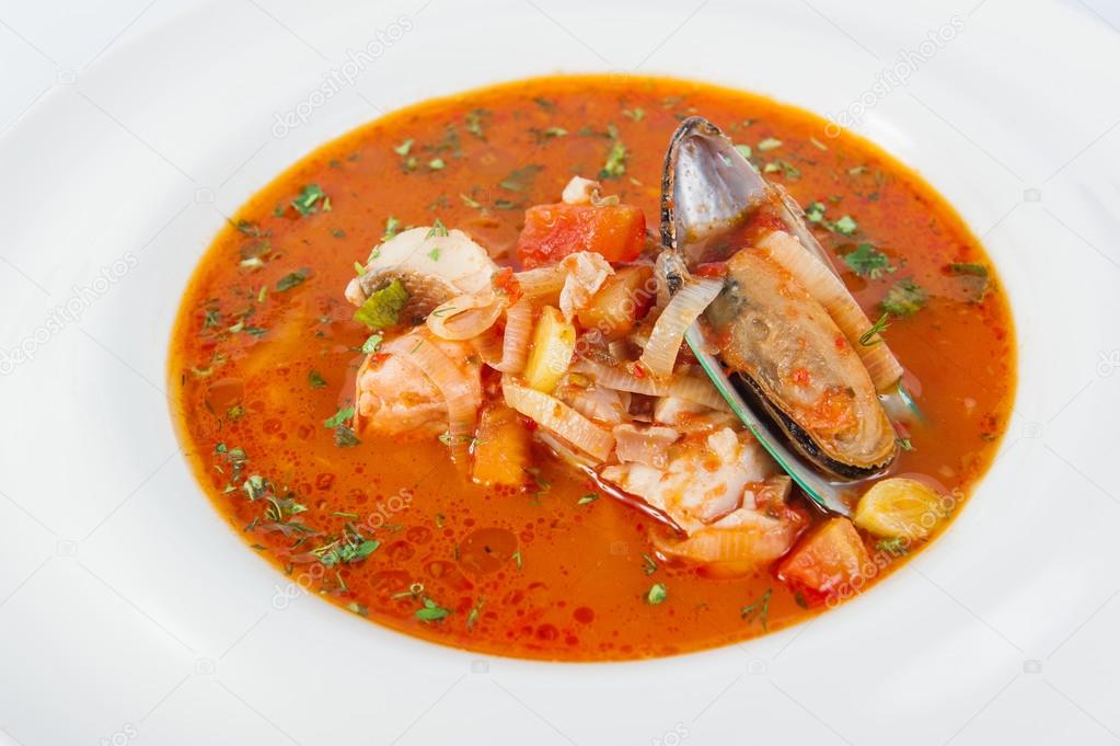 Close up Plate of Delicious Italian soup with seafood and vegetables decorated with herbs and shell mussel isolated on the white background