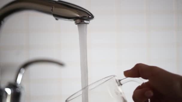 Pouring water into a glass in the kitchen — Stok Video