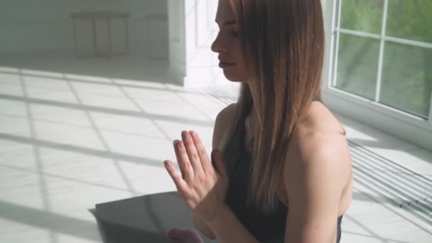 Wellness, młoda kobieta medytuje i uprawia jogę, spokojny nastrój, relaksując się w białym pokoju wypełnionym światłem, dziewczyna siedzi na podłodze. — Wideo stockowe