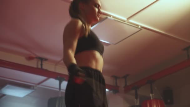 Női harci vonatok és ugrókötél, koordinációs tréning, kickbox edzésnap a boxteremben, erős testalkat. — Stock videók