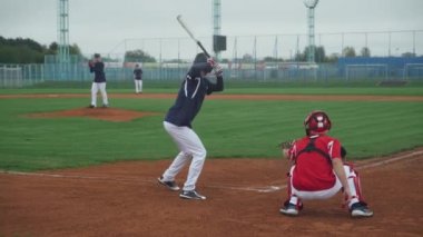 Üniversite sporları, beysbol oynayan erkekler, atıcı topu vurucuya doğru atar, vurucu başarılı bir şekilde hızlı topa vurur ve koşar..