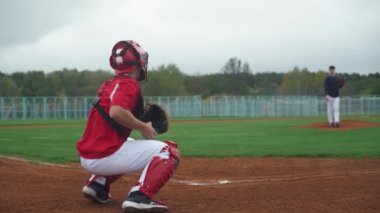 Kolej beyzbolu, atıcı topu yakalayıcıya doğru atıyor, tutucu topu başarıyla yakalıyor, beysbol oynamak için antrenman yapıyorlar,.