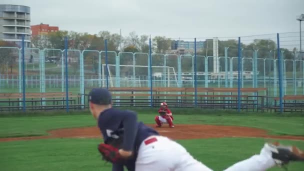 Baseball universitaire, le lanceur lance la balle vers le receveur, receveur avec succès attraper la balle rapide, les gars s'entraînent pour jouer au baseball, vue arrière. — Video