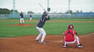 Kolej sporları, beysbol oynayan erkekler, atıcı topu vurucuya doğru atar, vurucu başarılı bir şekilde hızlı topa vurur ve kaleye koşar..