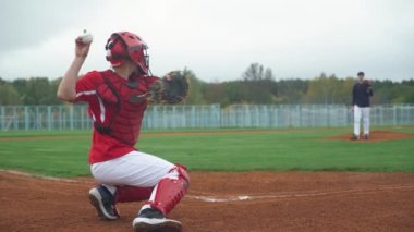 Kolej beyzbolu, atıcı topu yakalayıcıya doğru atıyor, tutucu topu başarıyla yakalıyor, beysbol oynamak için antrenman yapıyorlar,.
