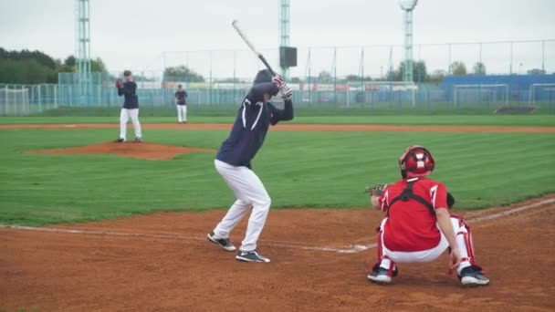 Спортивні коледжі, хлопці грають у бейсбол, пітчер кидає м'яч у бік батареї, батарея успішно влучає у швидкий м'яч і бігає на базу . — стокове відео