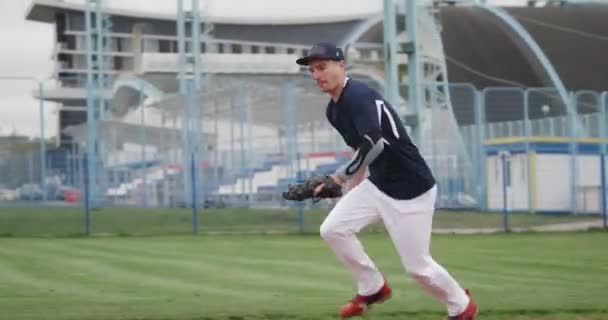 Beyzbol turnuvası, atıcı hızlı bir top yakalıyor, yere düşüyor ve pas gönderiyor, üniversitede spor.. — Stok video