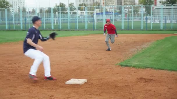 College, baseball träningsdag, catcher och löpare springa på basen, catcher är före löparen, killar tränar för att spela baseball. — Stockvideo