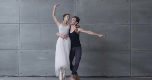 Elegancka para tancerzy baletu klasycznego tańczących na szarym tle, romantyczny taniec tancerzy baletowych, młoda para zaangażowana w choreografię. — Wideo stockowe