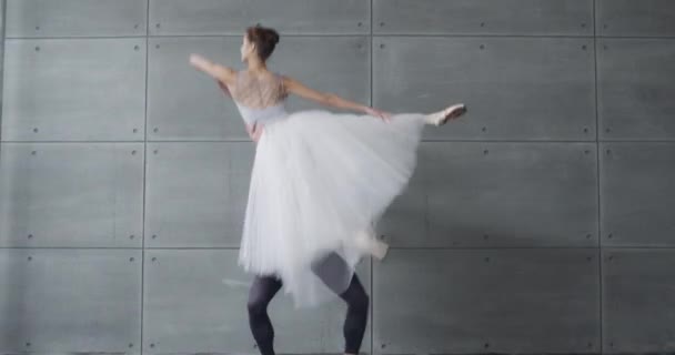 Elegancka para klasycznego baletu tańcząca na szarym tle, filmowe ujęcia romantycznego tańca baletnic, młoda para zaangażowana w choreografię. — Wideo stockowe