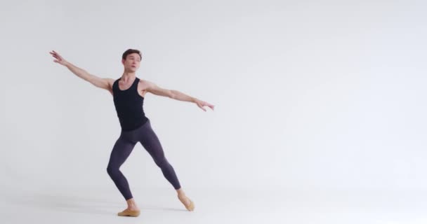 男性バレエダンサーは白い背景にバレエダンスのアクロバティックな要素を実行します。. — ストック動画