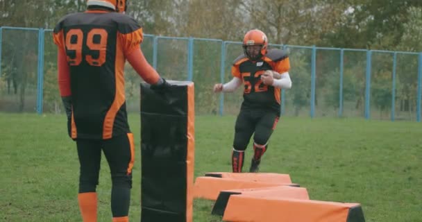 American Football, Fußballspieler in Schutzausrüstung springt über Hindernisse und hält den Ball in den Händen, Koordinationstraining, 4k 50fps. — Stockvideo