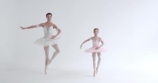 Vrouw en klein meisje in een witte tutu, dans ballet en choreografische elementen uit te voeren op een witte achtergrond, repetitie. — Stockvideo