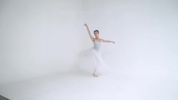 身着白色燕尾服的优雅女性，跳芭蕾舞，在白色背景下表演舞蹈元素，排练. — 图库视频影像