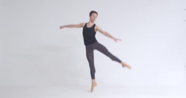 Jonge man, ballet danser voert pirouette en acrobatische elementen in ballet dans, witte achtergrond. — Stockvideo