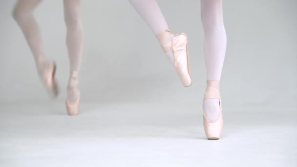 Kvinna och liten flicka i en vit tutu, balansera i Pointe skor, vy över benen, vit bakgrund. — Stockvideo