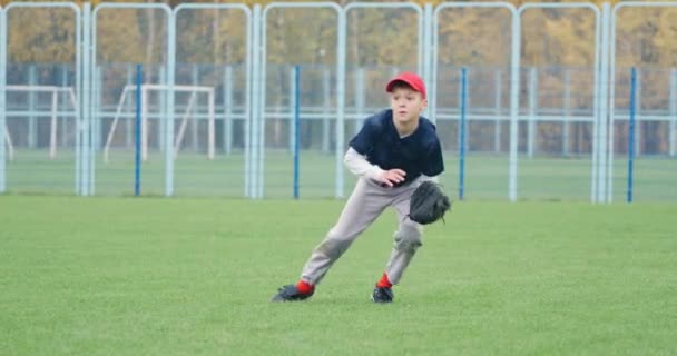 Turniej baseballowy w szkole, miotacz chłopiec łapie szybką piłkę w rękawicy i wysyła przepustkę do innego gracza, dynamiczna gra sportowa. — Wideo stockowe