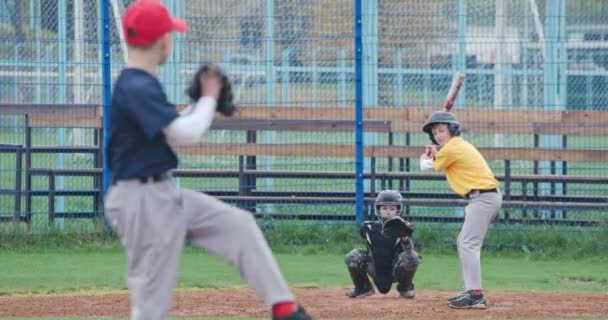 Baseballový turnaj ve škole, kluci hrají baseball, nadhazovač hodí míč na pálku, pálkař úspěšně trefí rychlý míč. — Stock video