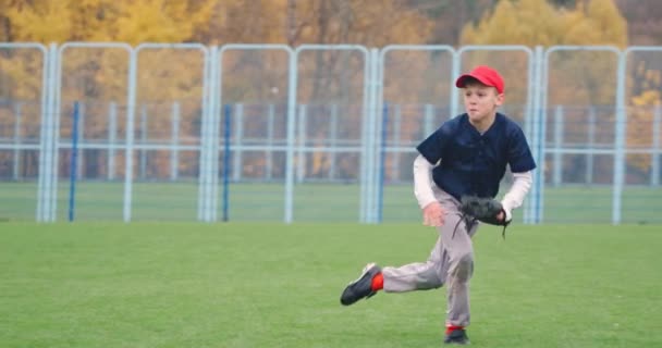 Tournoi de baseball à l'école, le garçon lanceur attrape avec succès une balle rapide dans le gant et envoie une passe à un autre joueur, 4k au ralenti. — Video