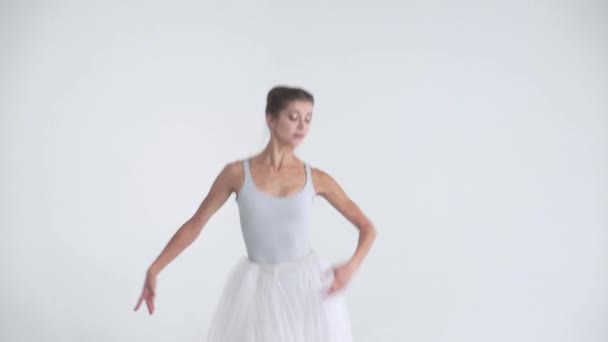 Elegancka kobieta w białej spódniczce, tańczy balet i wykonuje elementy choreograficzne na białym tle, próby. — Wideo stockowe